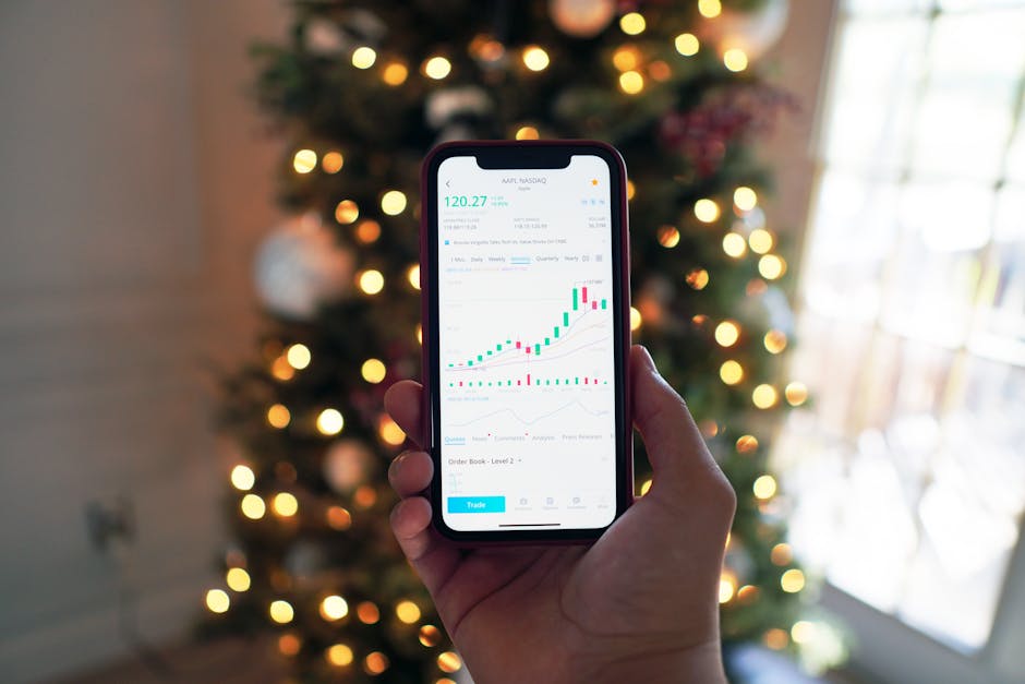 Close-up of a smartphone displaying stock market trading app with a background of Christmas lights